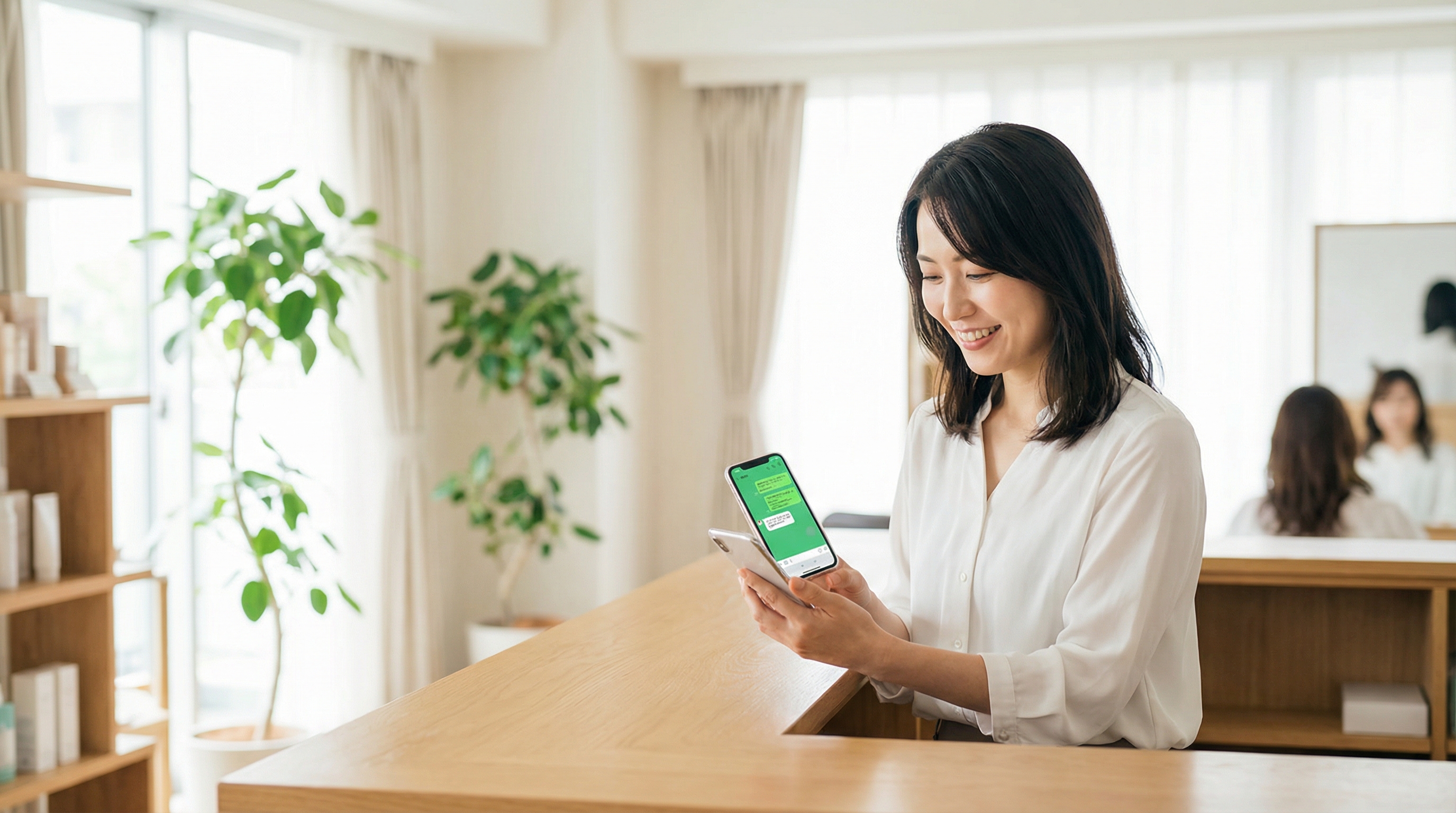 サロンでスマートフォンを使って顧客対応する女性スタッフ
